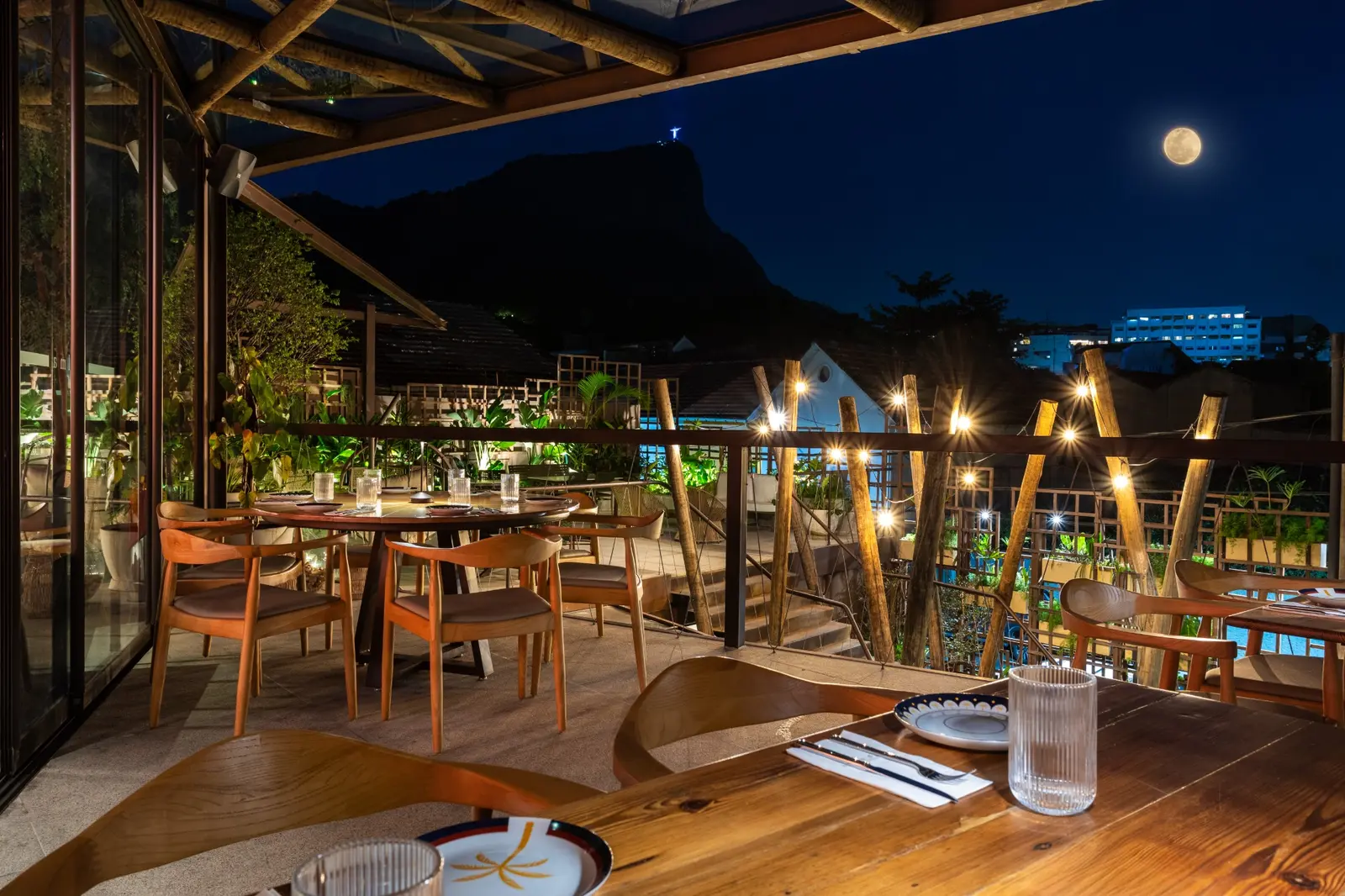 Terraço da Casa Horto à noite, com mesas postas e vista para o Cristo Redentor